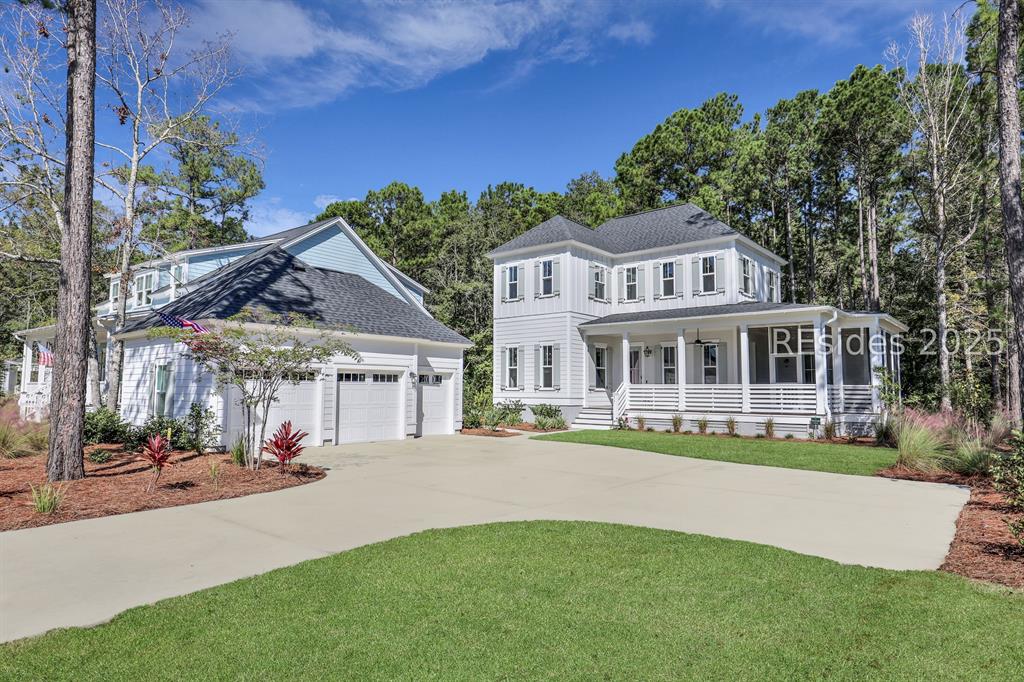 Bright white Lowcountry home with three-car garage and wraparound porch on a manicured lawn