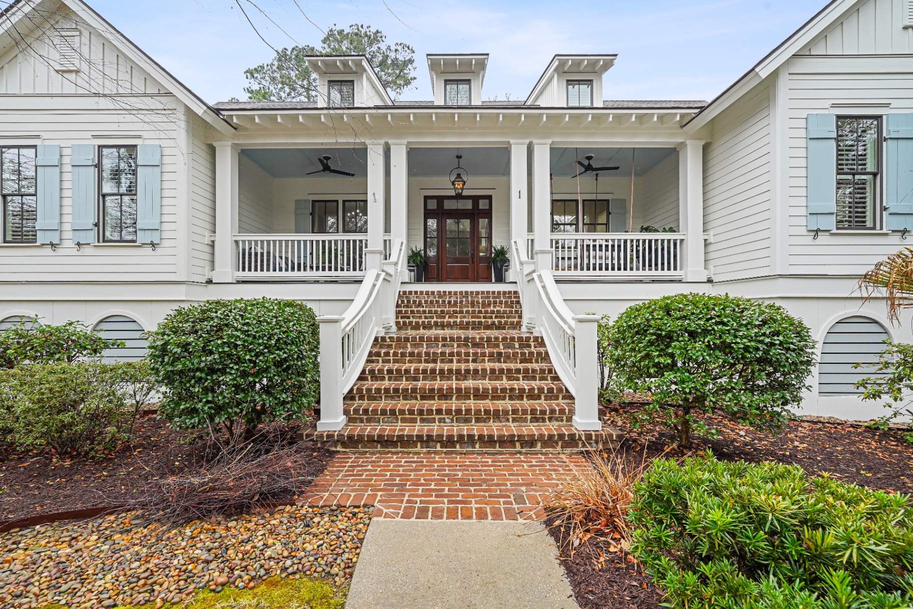 White Lowcountry home with grand brick staircase and blue shutters