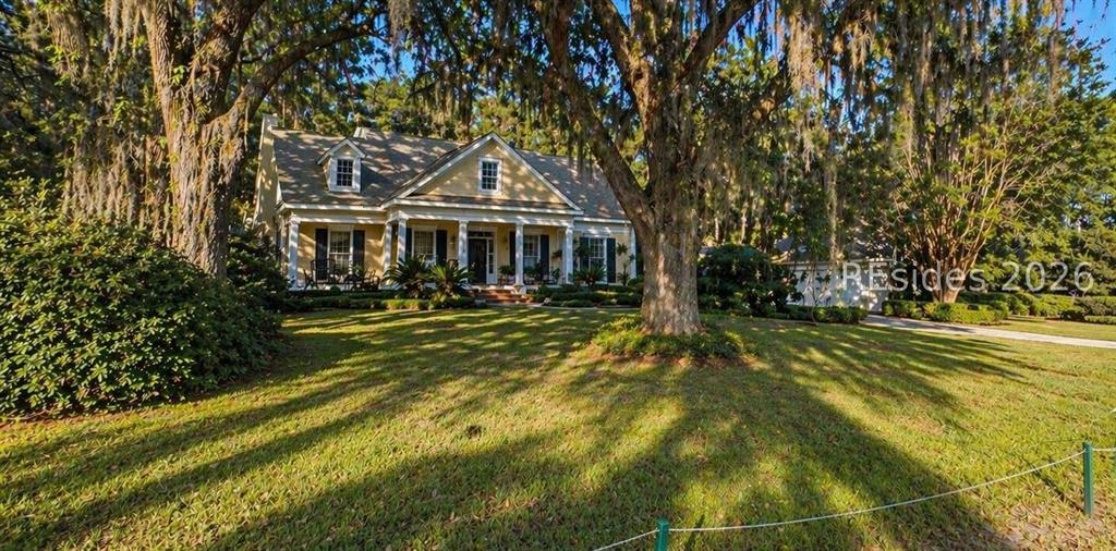 Yellow Lowcountry home with white columns and Spanish moss-draped oak trees on a spacious lawn